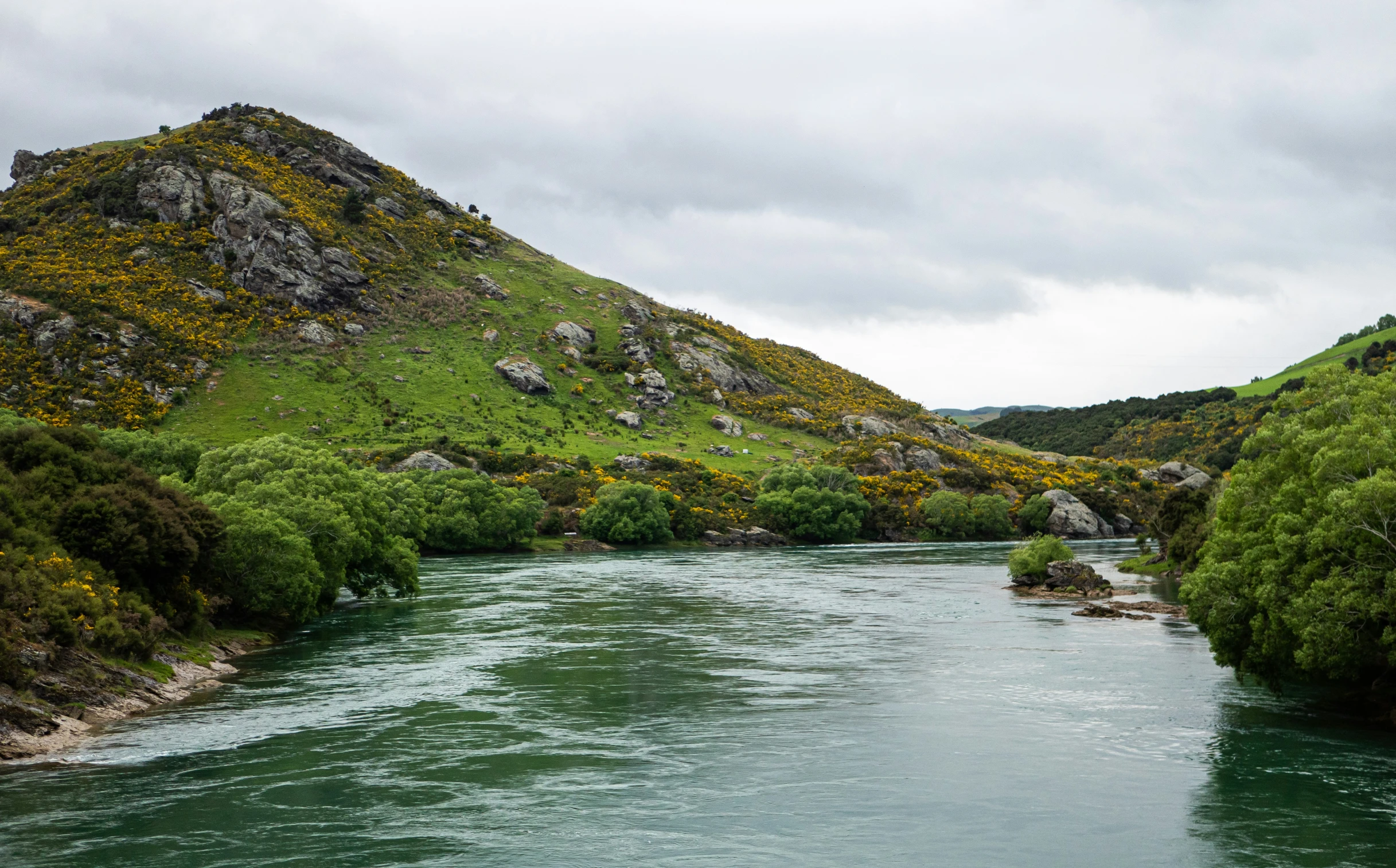 the view of a river with green mountains in the background