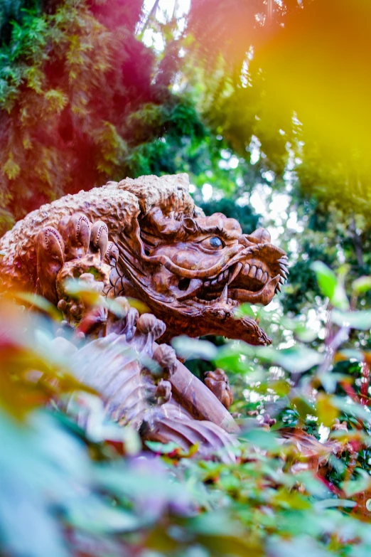 a wooden dragon sitting next to green leaf covered trees