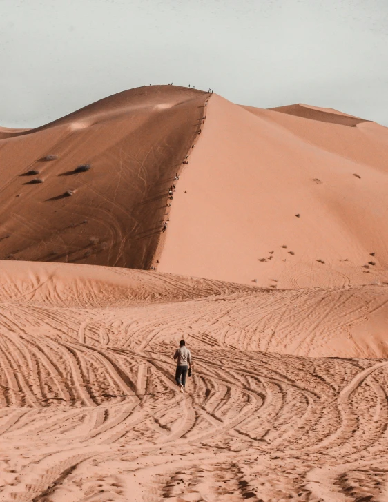 there is a large dune with some tracks in the sand