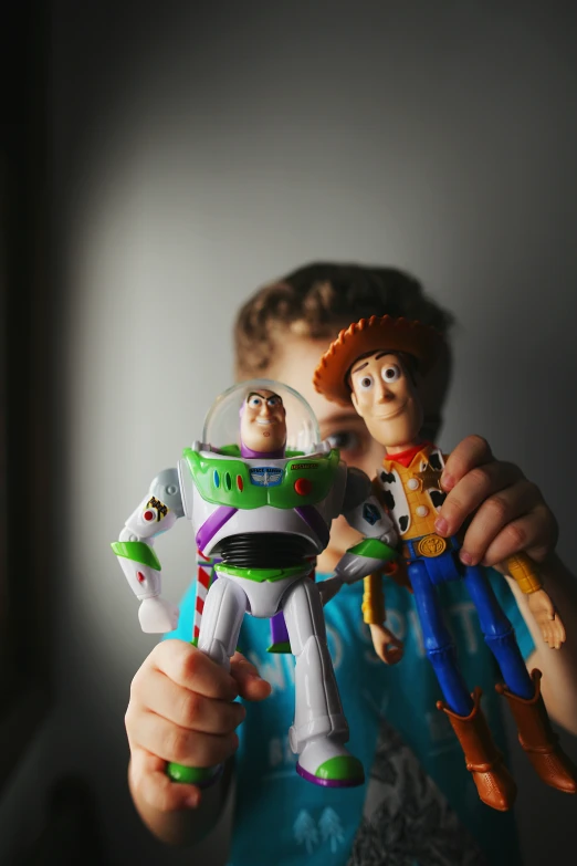 a little boy holding a toy next to buzz lightyear