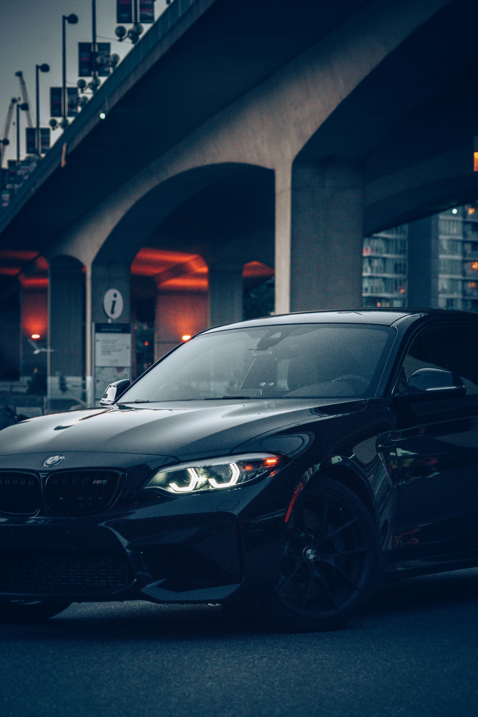 a dark colored car parked in front of an overpass