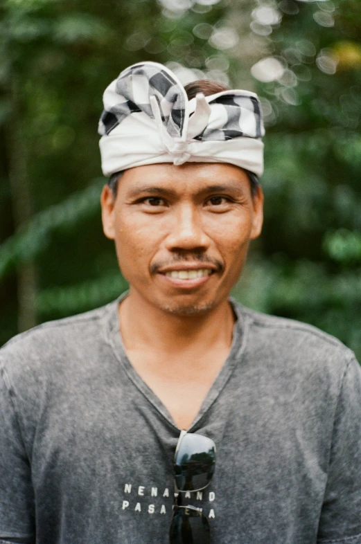 man wearing tie and bandana standing in front of trees