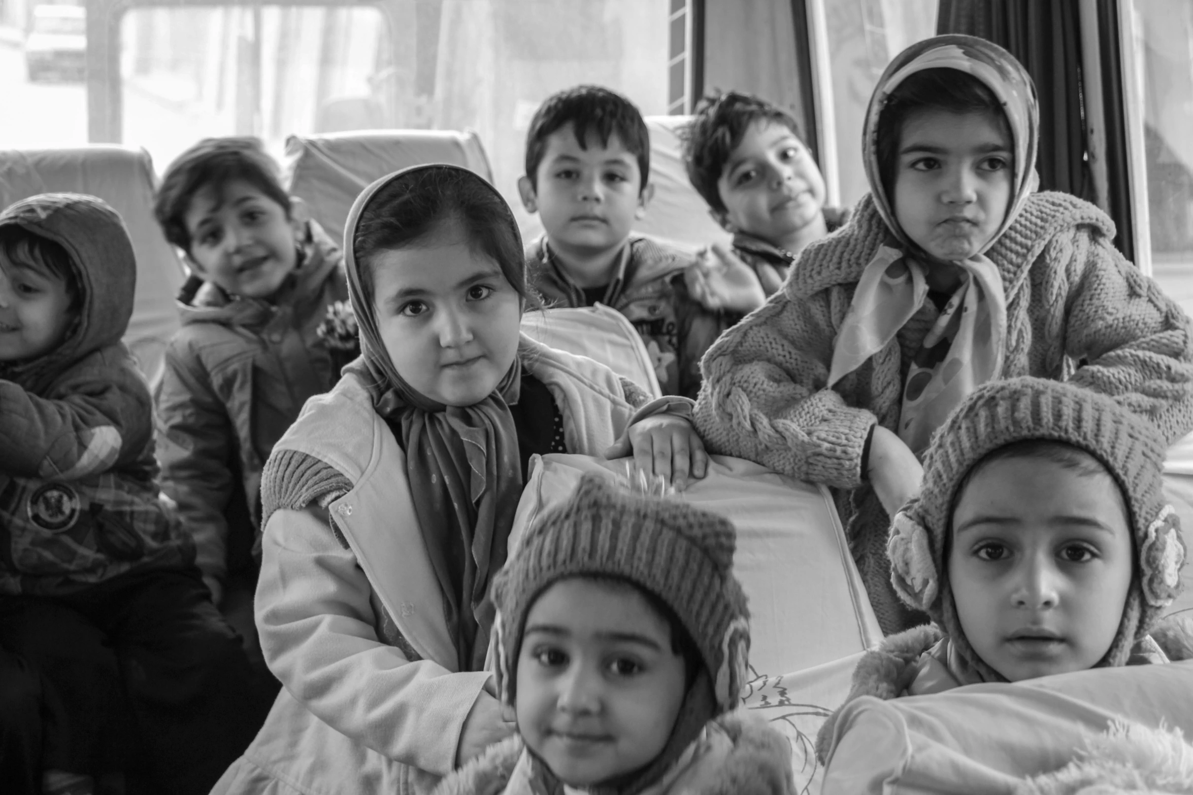 the group of children in beanie hats are all sitting down