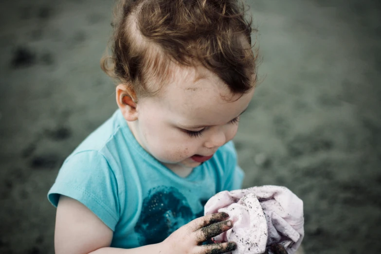 a young child holding and looking at a piece of material