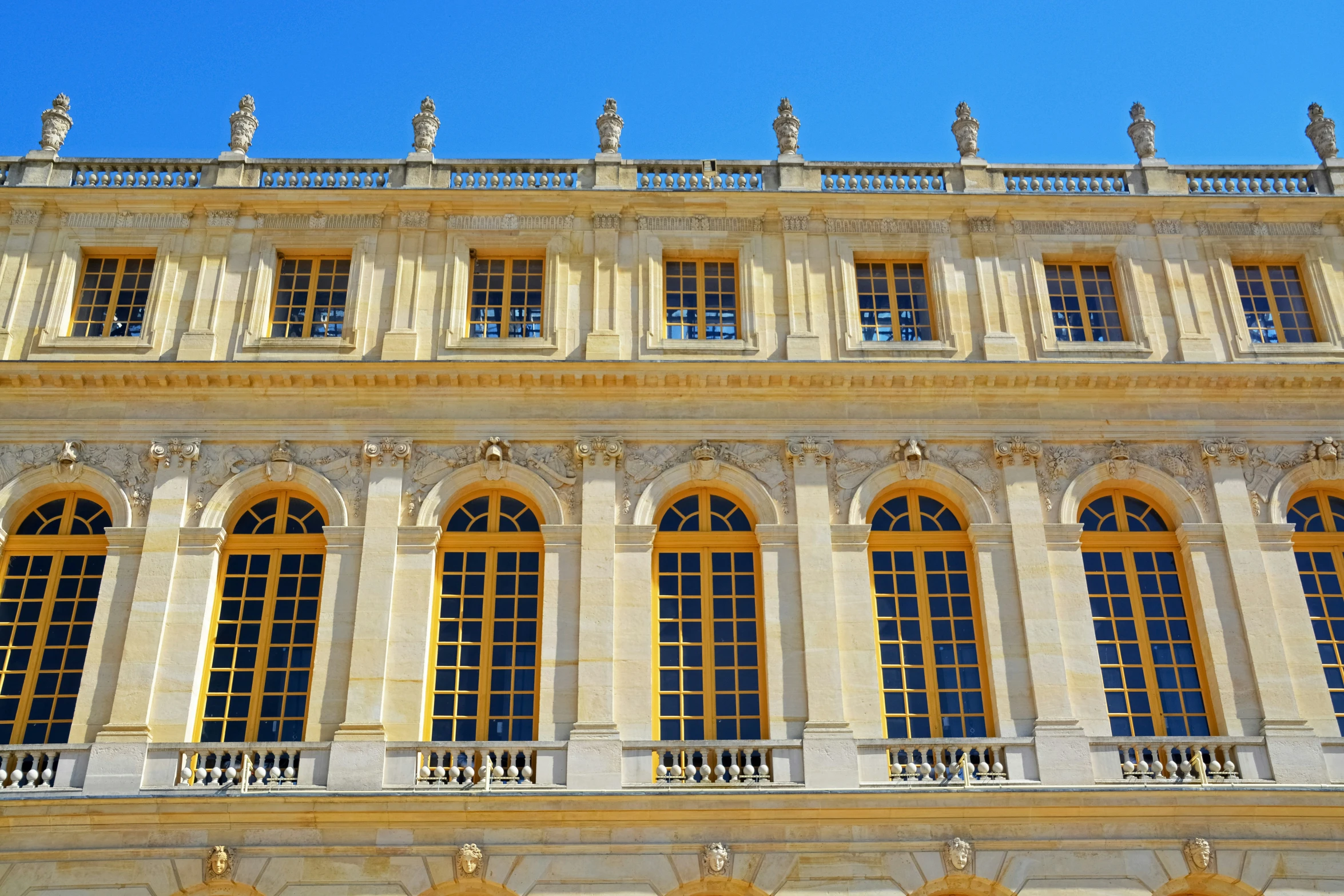 the large building has many windows and statues around it