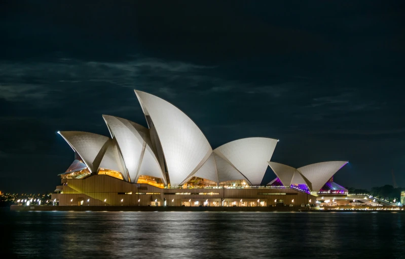 the sydney opera house lit up at night with lights on it