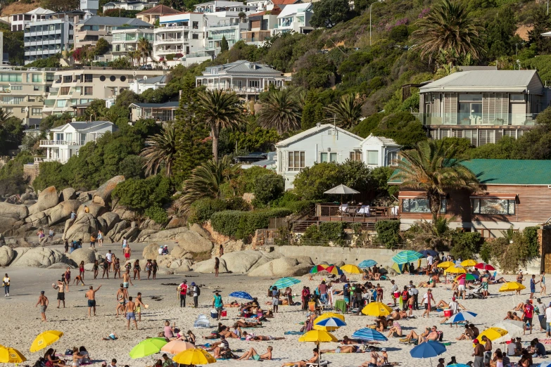 people are in a crowded beach with buildings in the background