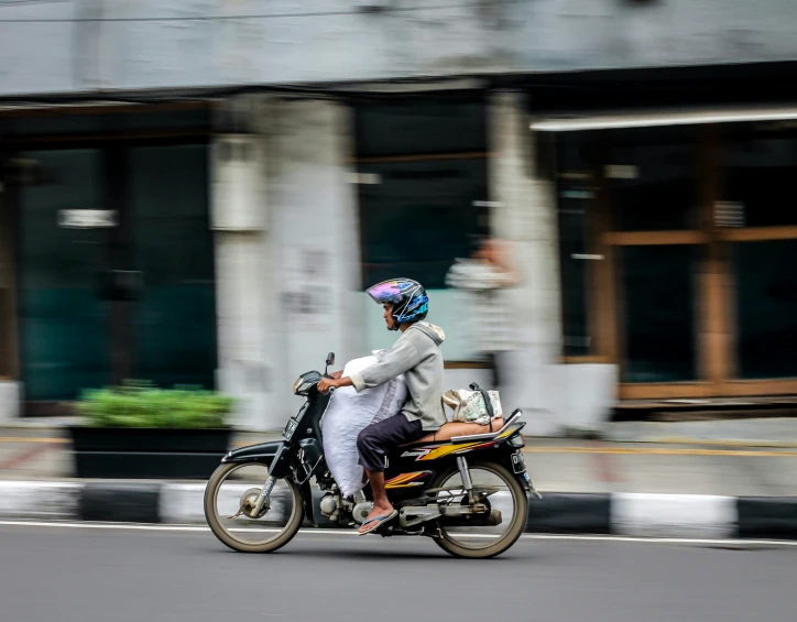 two men riding on a motorcycle in the street