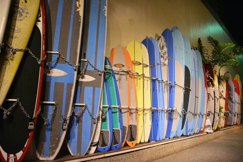 many different surf boards are hung up behind the wall