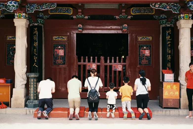 a group of people standing on a sidewalk in front of a building