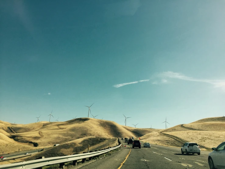 cars driving on the road by wind turbines