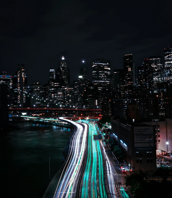 many cars traveling down the street below a city skyline at night