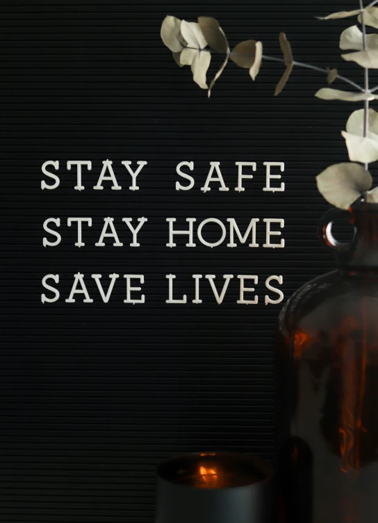 a vase with flowers sits next to a sign that reads stay safe stay home save lives