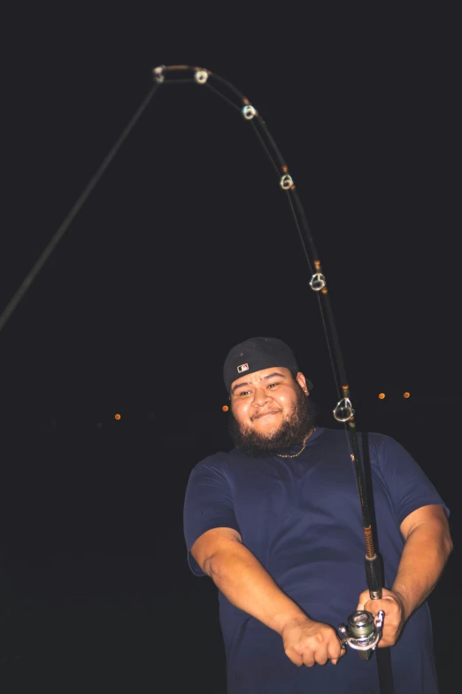 a man smiles while holding onto a fishing rod