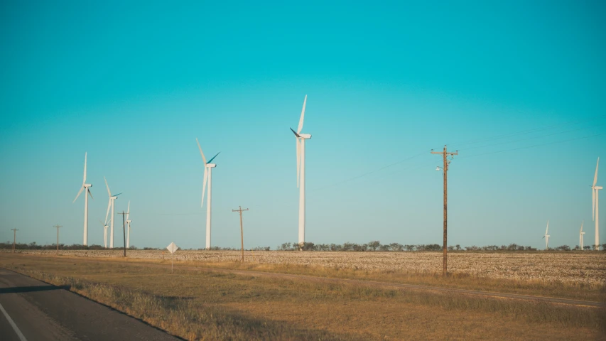 four windmills in an open field with a road running past them