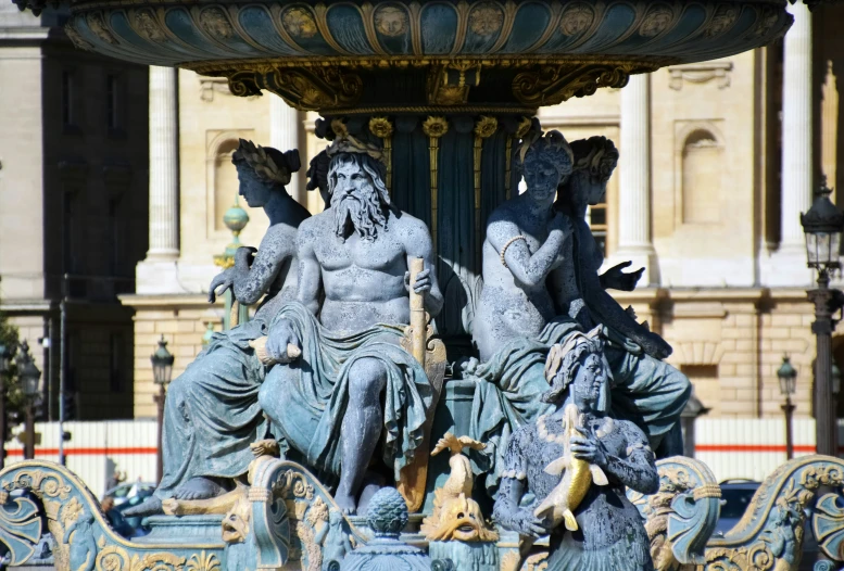 an ornamental fountain with sculptures in front of a building