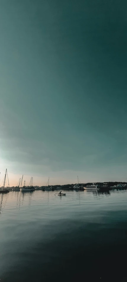 sail boats in a harbor are sailing towards the sun