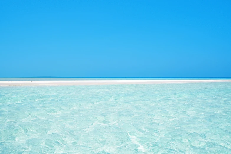 view over bright blue ocean water towards distant beach area