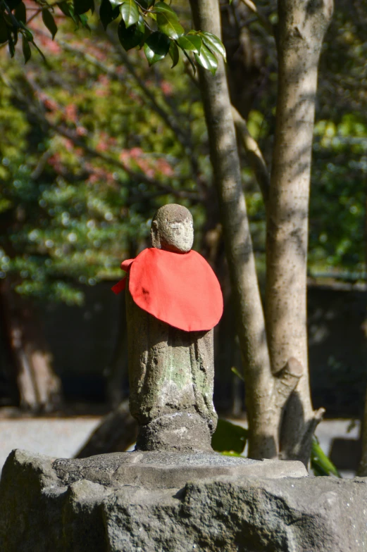 a statue in front of trees holding a red frisbee