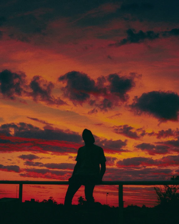 silhouetted person standing in front of orange and blue sky