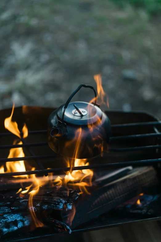 a kettle sits on the fire as the fire burns