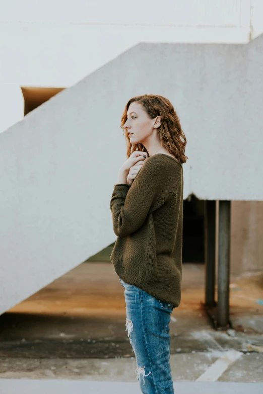 the woman is posing for a picture in front of a stair case