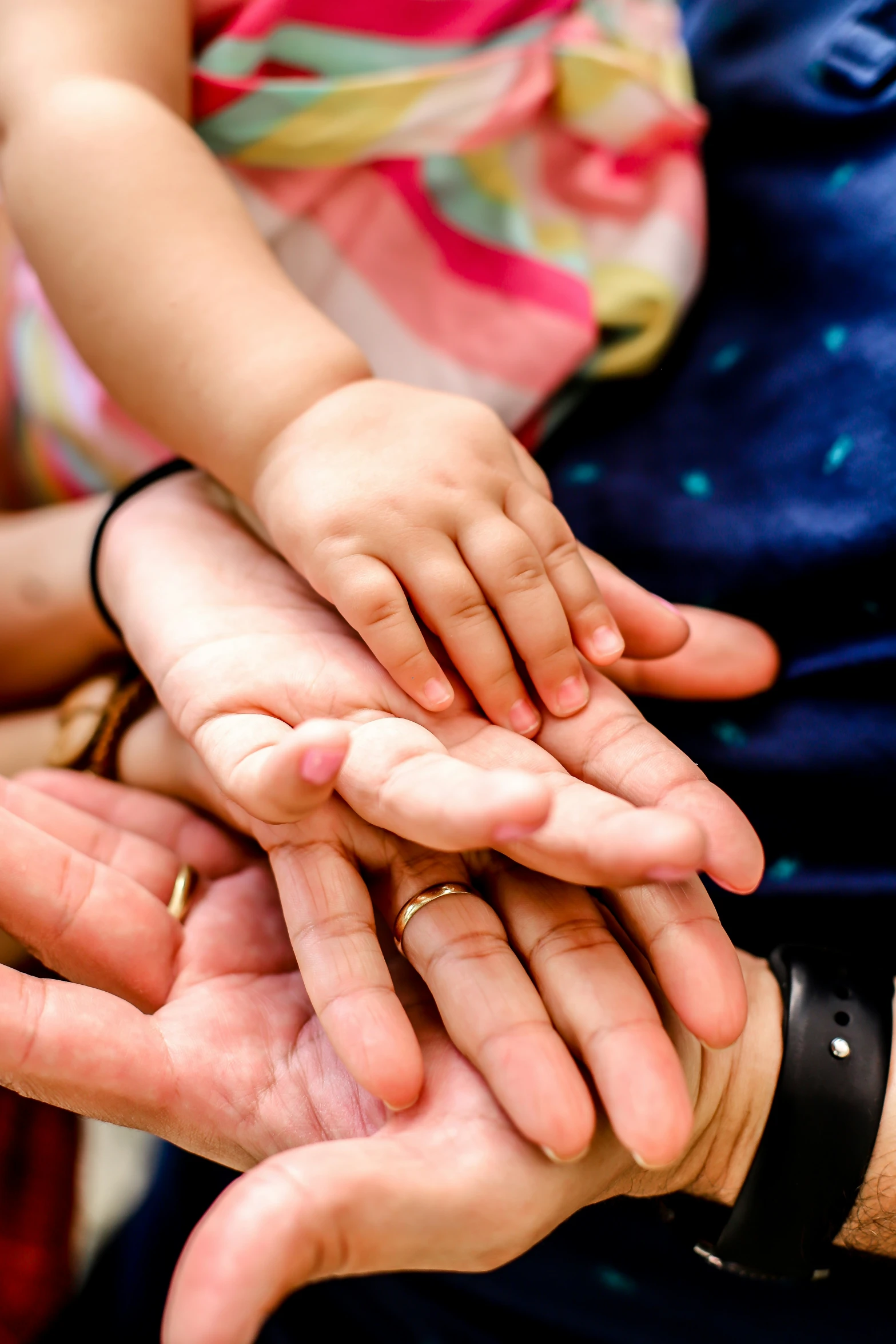 several hands holding soing together, showing a wedding band