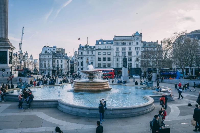 people are gathered in a public square with fountain