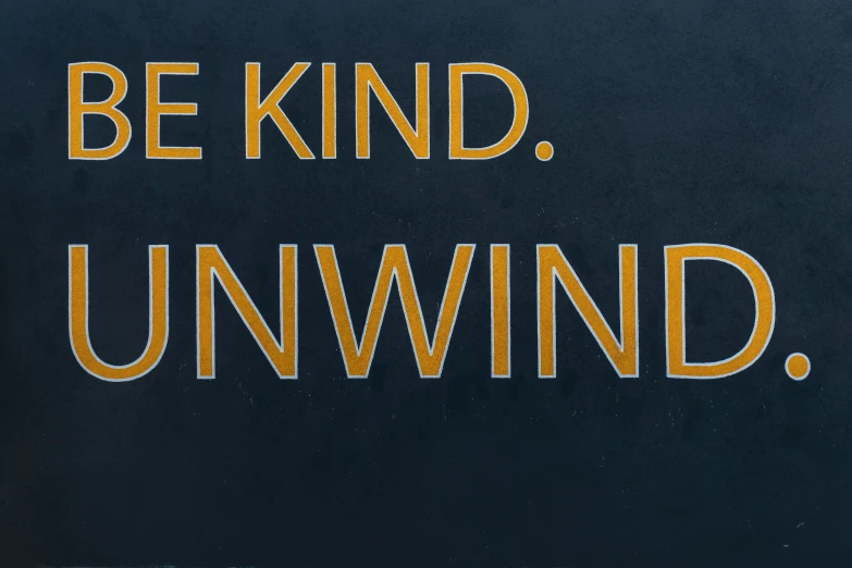 a yellow and black sign saying be kind, unwind
