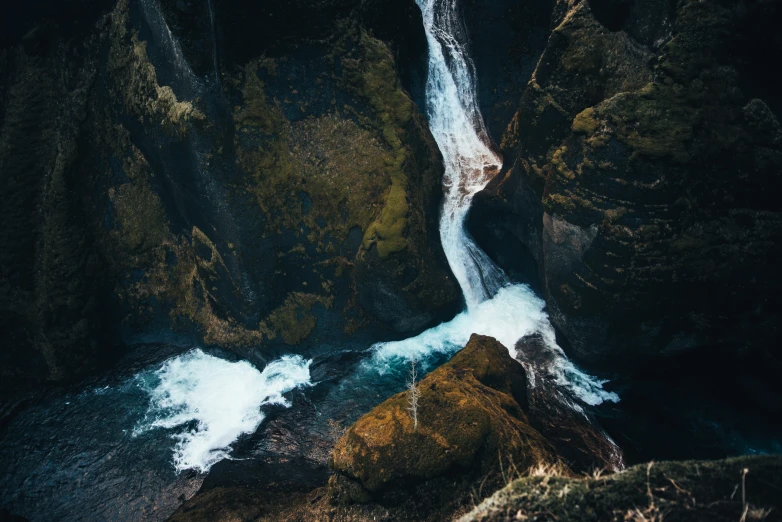 a waterfall in the middle of rocks with a man on it