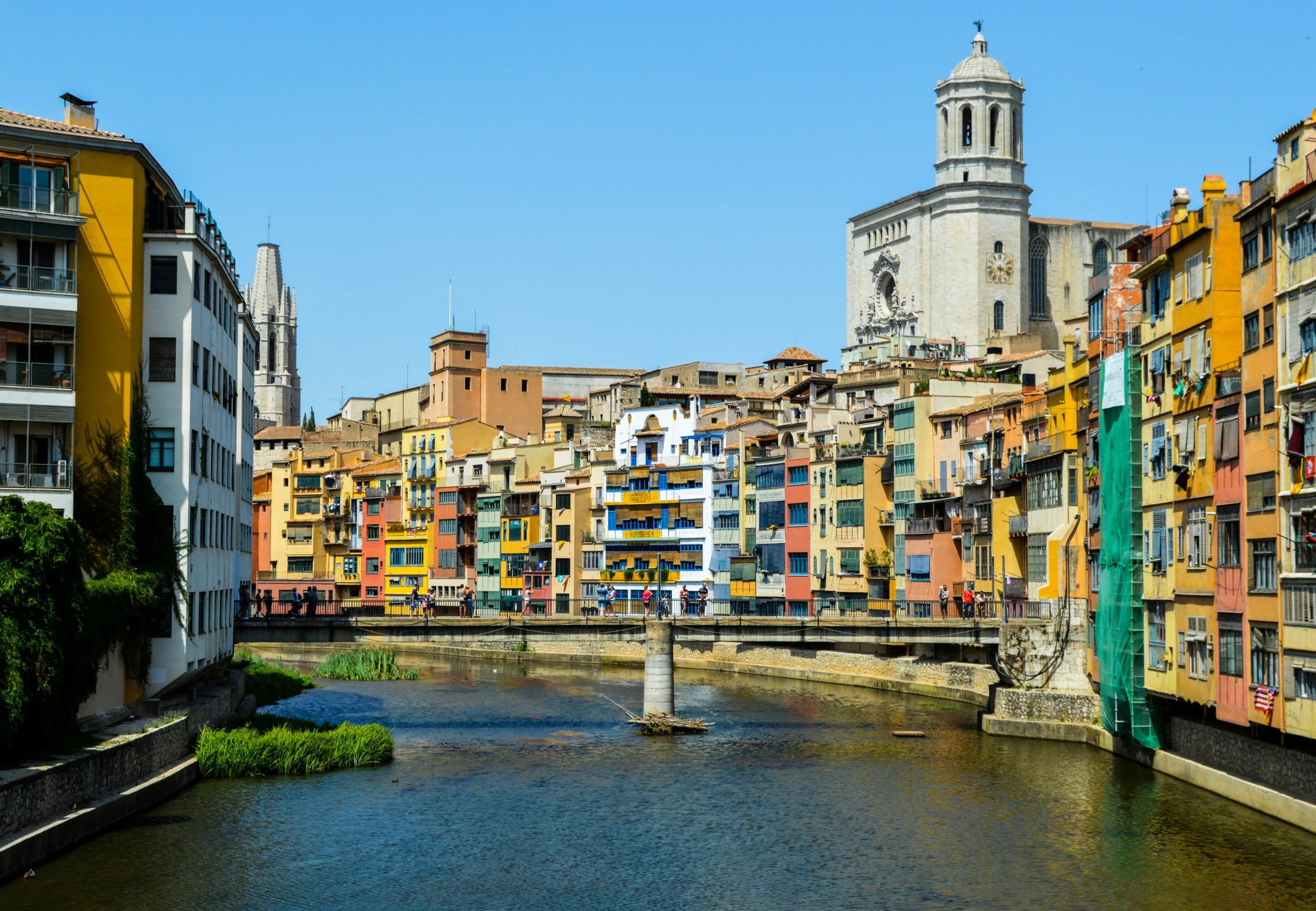 many buildings near a body of water with a bridge in the middle