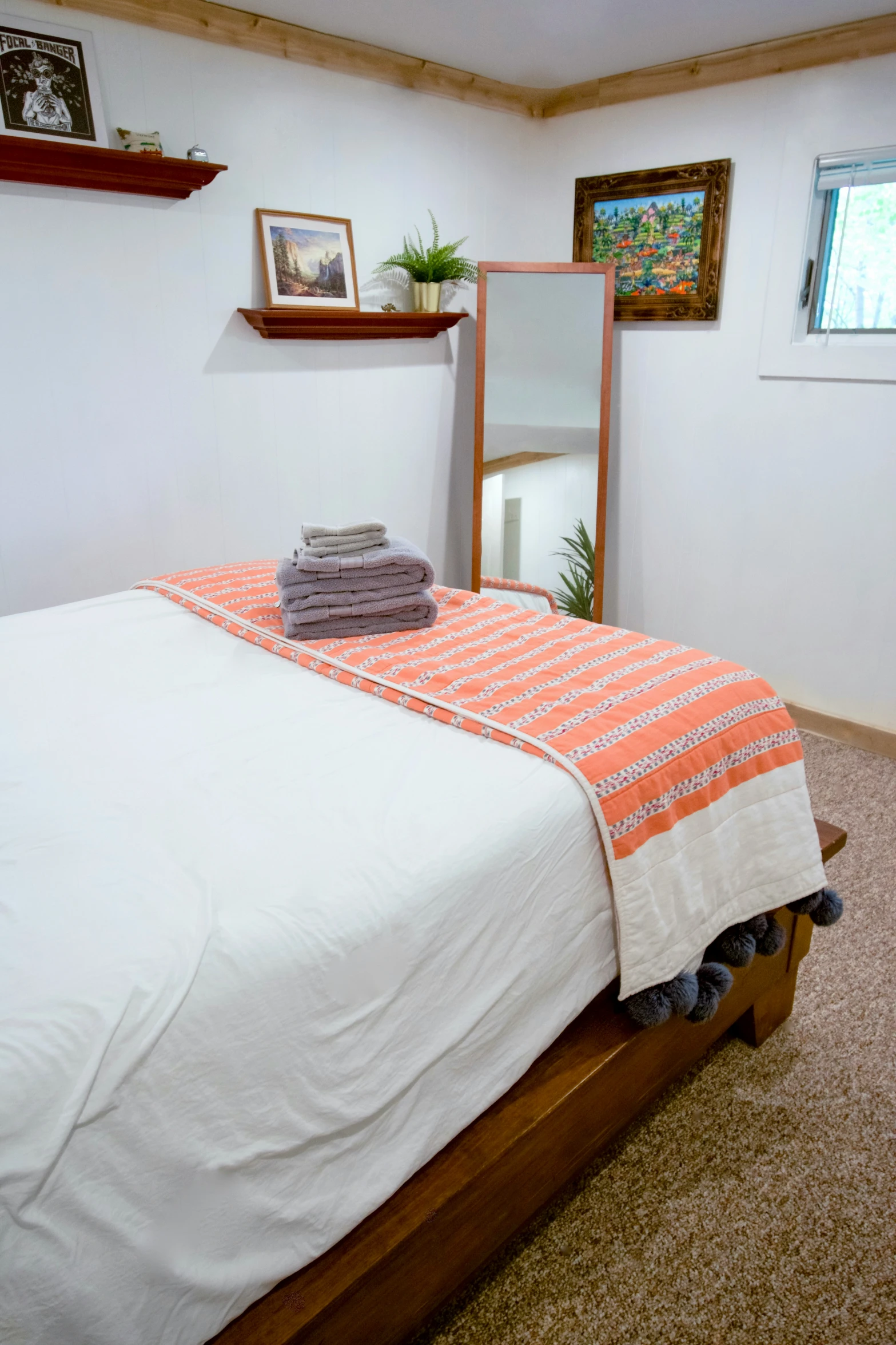 this bed has white sheets, a wooden frame and an orange throw blanket