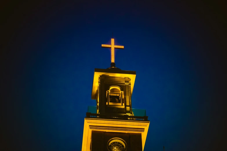 an illuminated tower with a cross on top