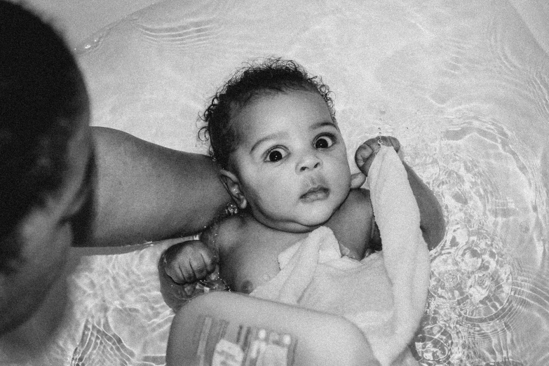 baby in the crib next to her dad's head and a person holding his hand out