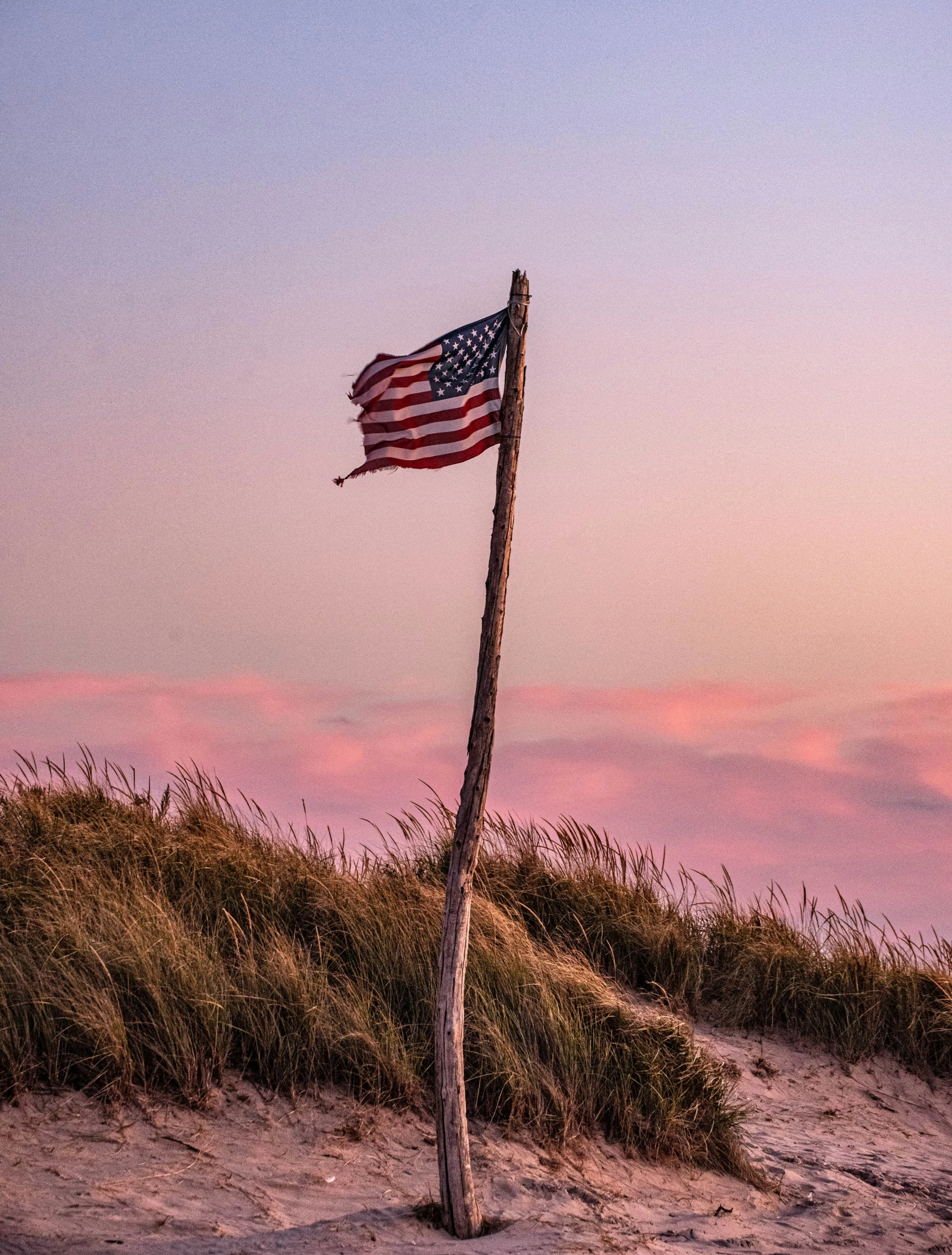 an american flag in the sand on top of a hill