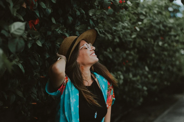 a woman standing next to trees looking up into the sky