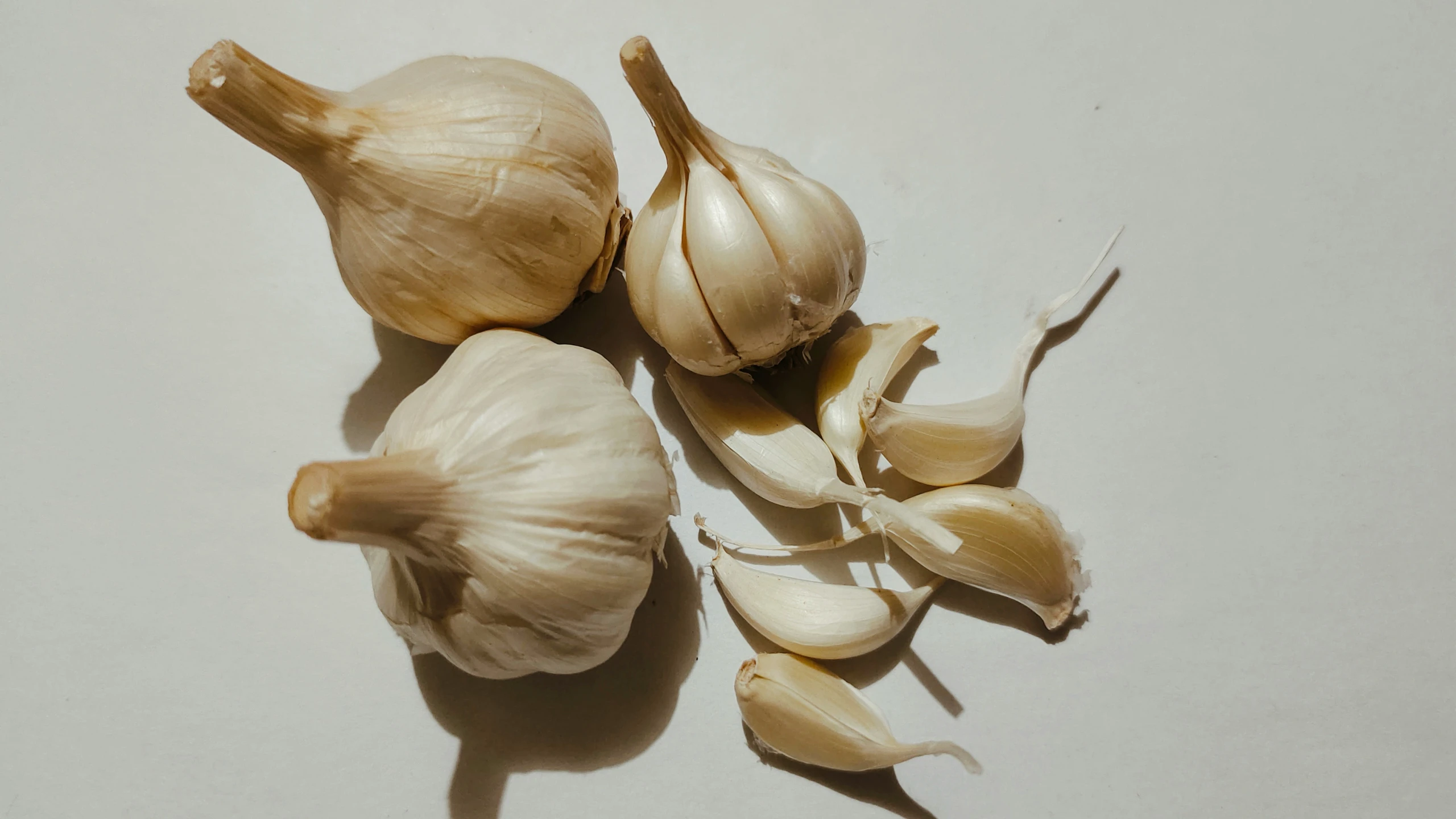 garlic and clump of fresh garlic on a white surface