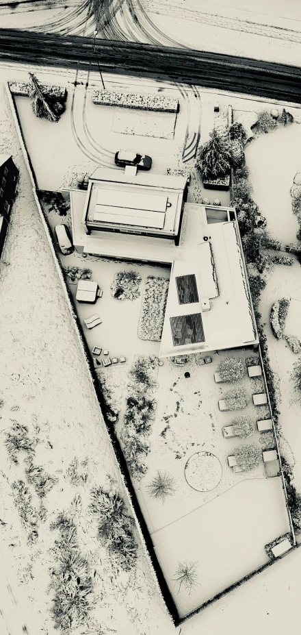 a picture looking down at a snow covered yard, driveway and buildings