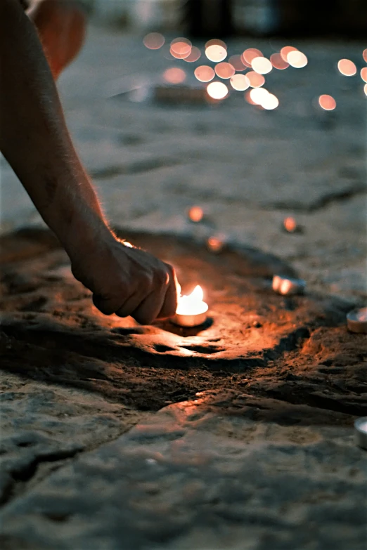 a person holding candles in their hand on the ground