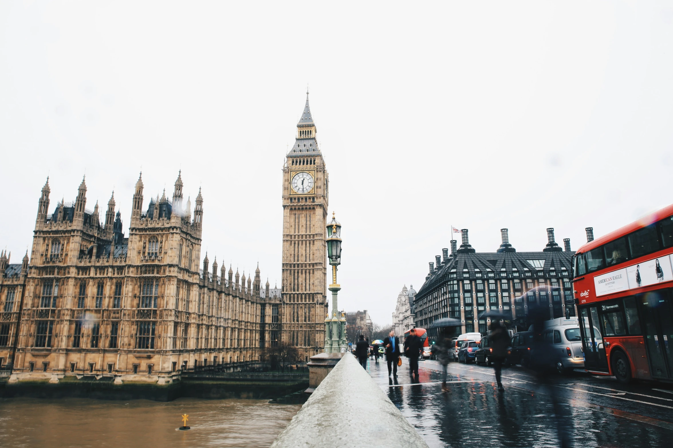 people walking down a rainy street next to a clock tower