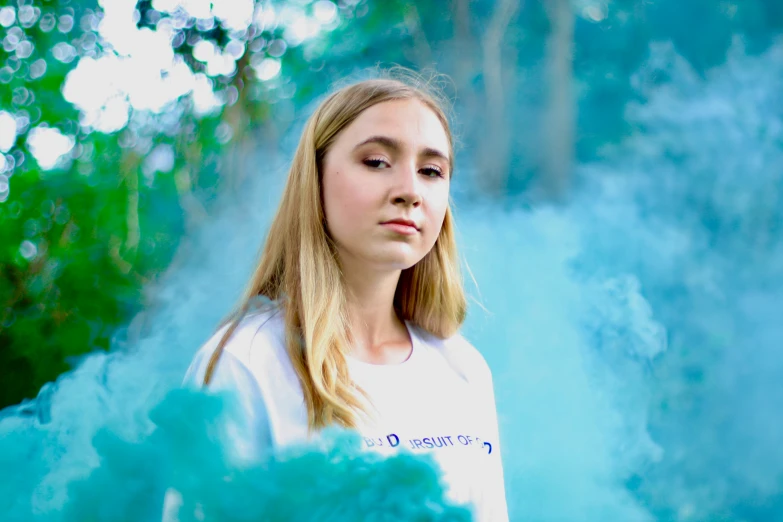 girl staring ahead among the blue smoke in the forest