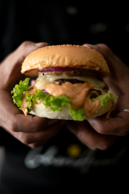 two hands holding an up close s of a hamburger