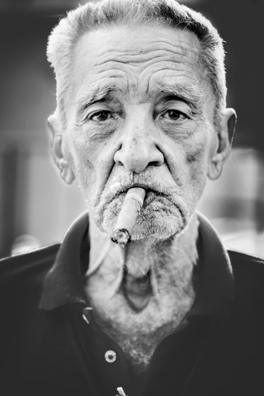 an elderly man poses with a pipe in his mouth