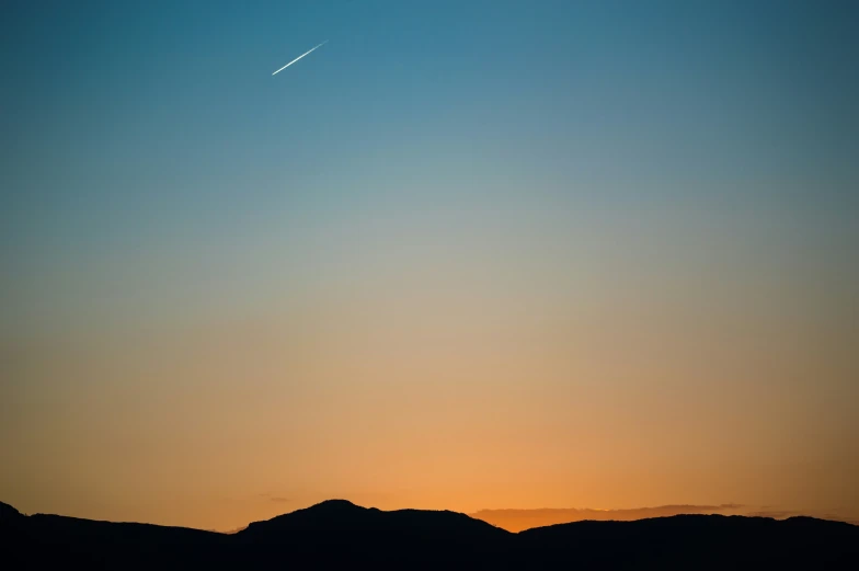 a plane flying through the sky at dusk