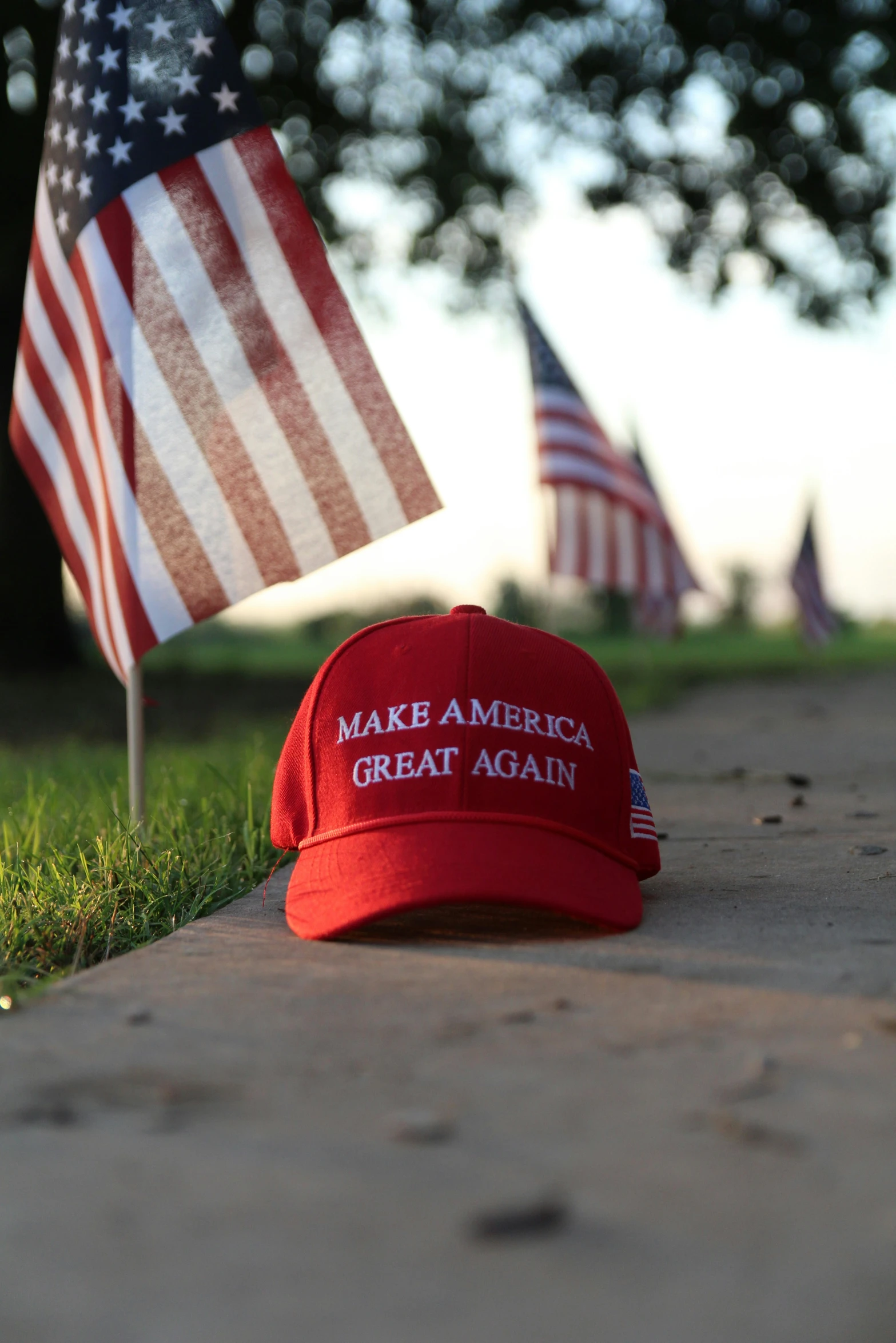 an american flag is sitting on a stone surface next to a hat