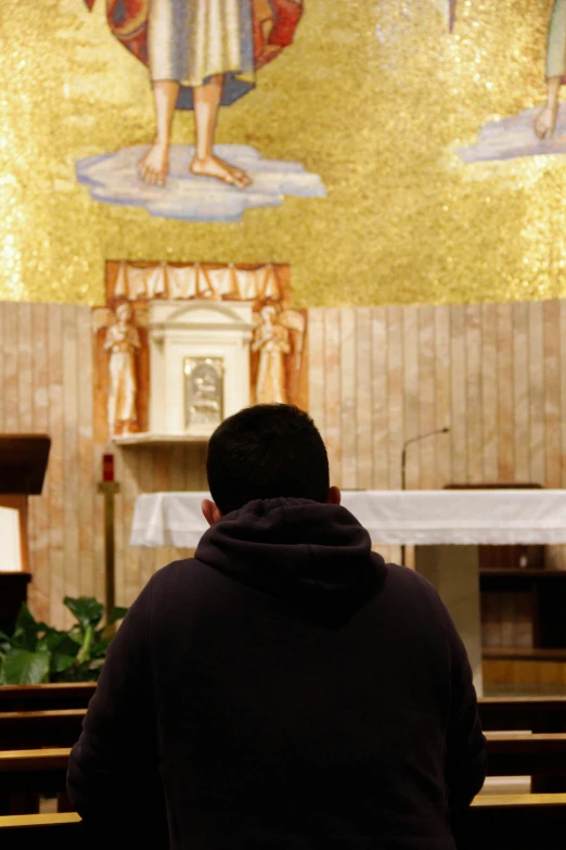 a man in front of a wall of stained glass with gold mosaics