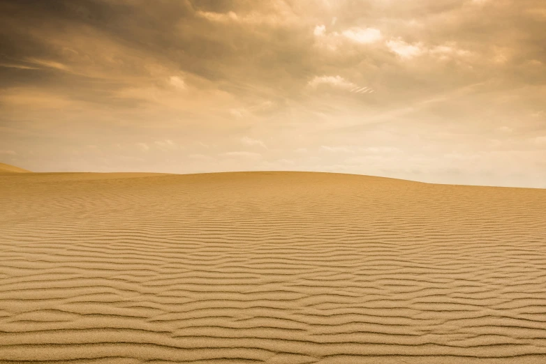 sand is moving in the desert under cloudy skies