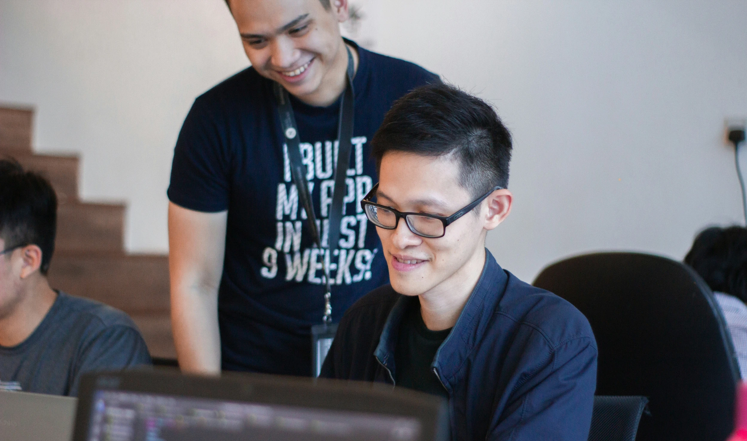 two guys in a room with computers smiling