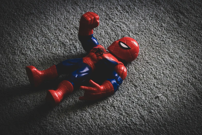 toy spider man laying on gray carpet