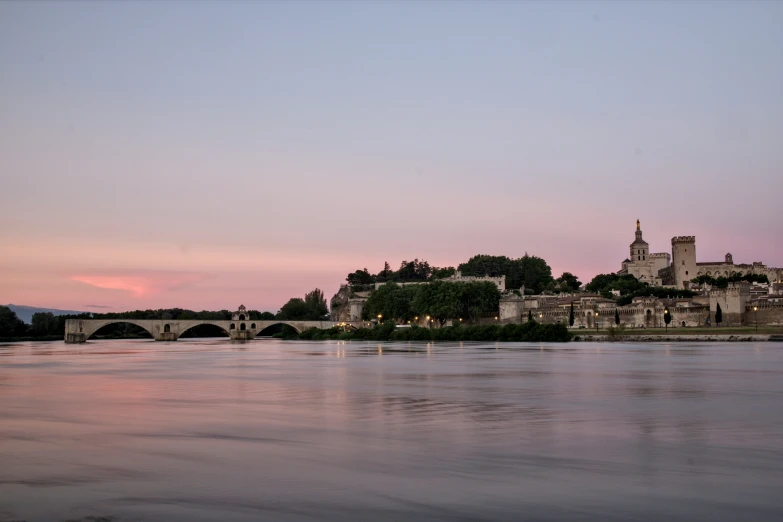 an old town lit up at dusk and reflecting on water